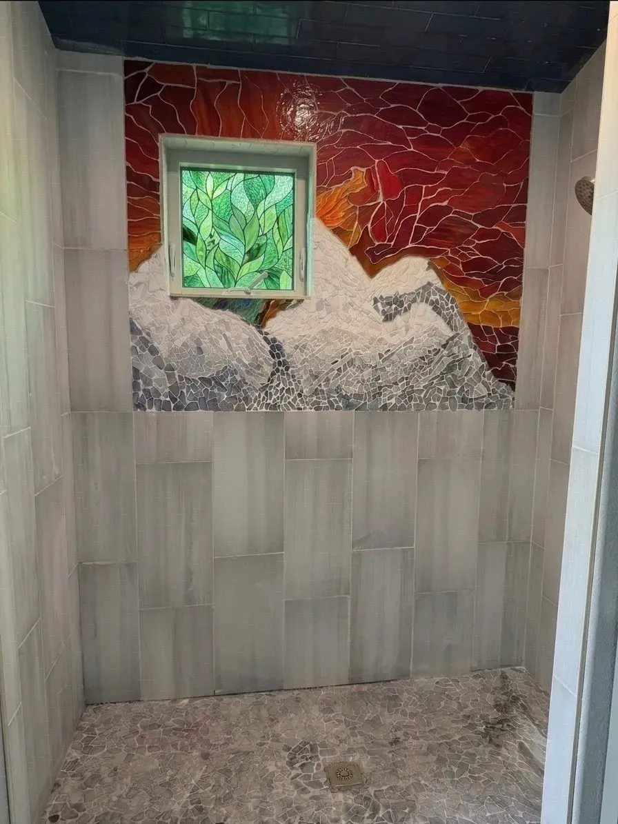 Alpine Sunset hand-cut glass mosaic across a shower wall