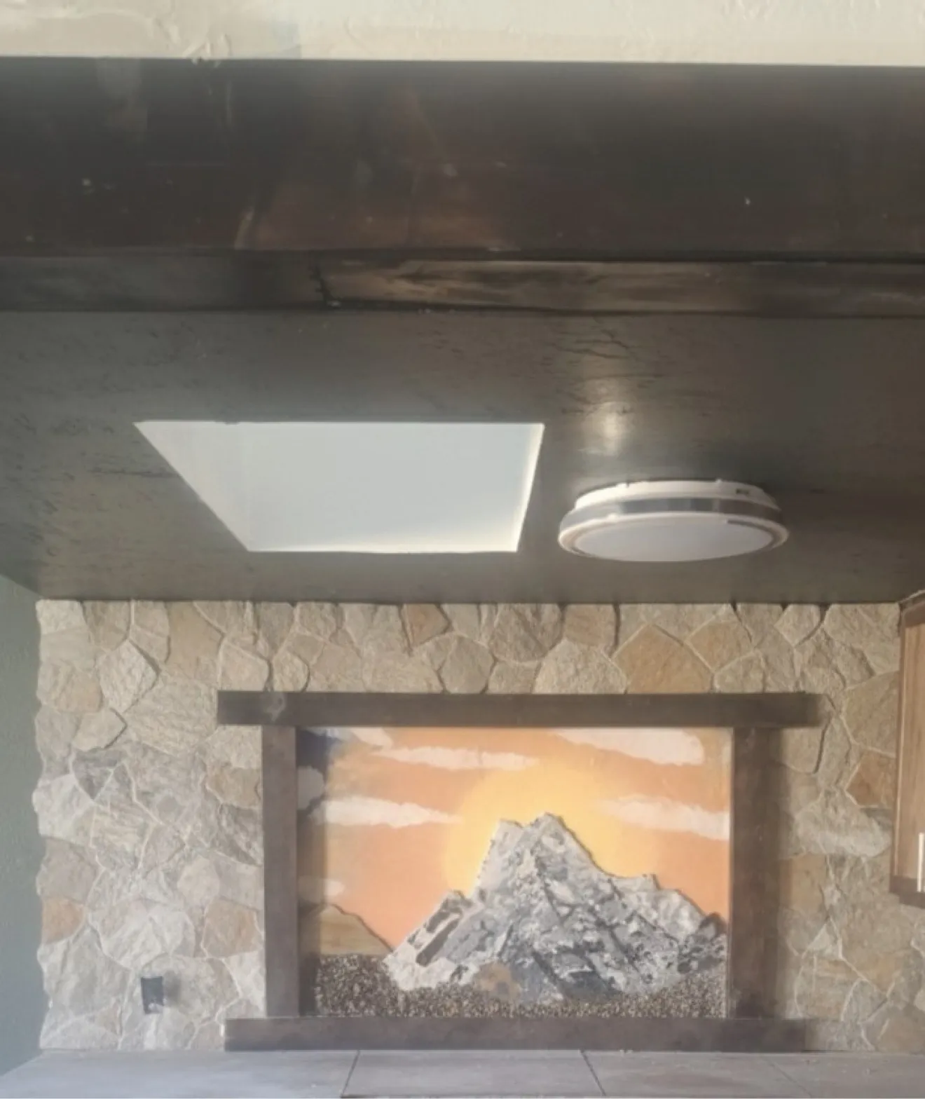 Stone mosaic fireplace surround with mountain sunset scene